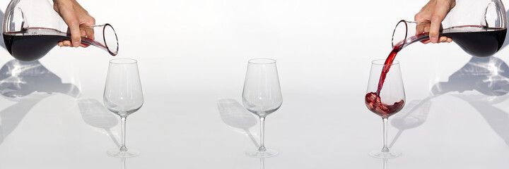 Sommelier pours red wine from decanter to wineglass on white background. panoramic shoot or banner.