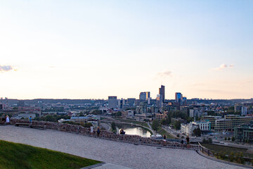 Obraz premium Ruins of a fortress on the mountain. Vilnius. Observation place on the mountain. People are resting and looking down at the city. Young couples spend time together. View of the city from the hill.