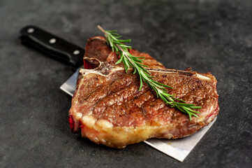 grill t-bone steak with ingredients on a meat knife on stone background