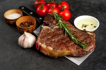 grill t-bone steak with ingredients on a meat knife on stone background