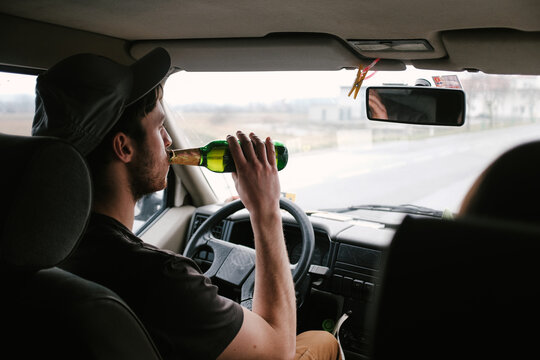 Drinking beer behind steering wheel of car