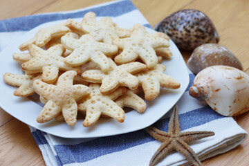 Salty cheese cookies in shape of a starfish on a plate on wooden table
