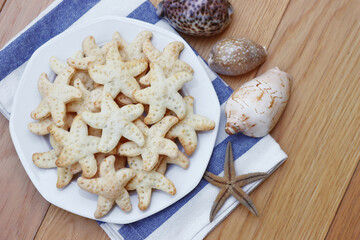 Obraz na płótnie Canvas Salty cheese cookies in shape of a starfish on a plate on wooden table 