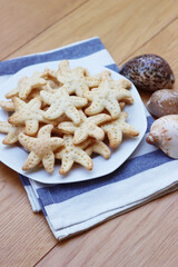 Salty cheese cookies in shape of a starfish on a plate on wooden table

