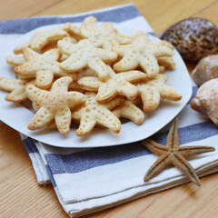 Salty cheese cookies in shape of a starfish on a plate on wooden table
