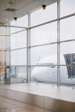 Airplane embarking passengers seen through the window of an airport