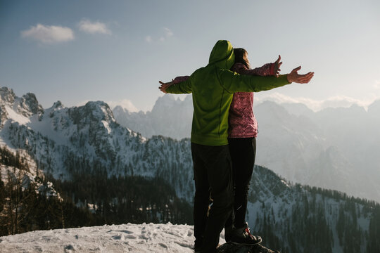 Couple holding like in titanic on top of mountain covered by snow
