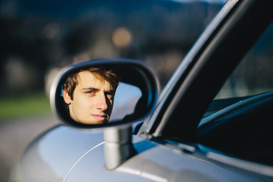 Reflection of a young man in the side mirror of a sports car