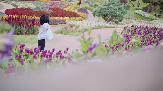 wide shot Asian beautiful young woman jumping and spinning inside colorful flower garden, feeling fresh and joy, moment inside floral garden farm, happy enjoy relaxing trag woman in lavender field