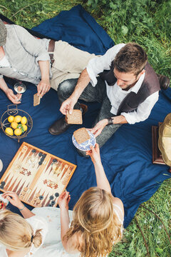 Spring Picnic - Overhead of Five Friends on Blue Quilt Sharing Food and Drink Outdoors