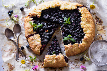 Homemade crispy blueberry pie or galette and mint.  Summer, bright, delicious pies framed with flowers and herbs with berry