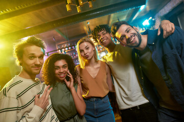 Smile. Portrait of young men and women looking at camera and smiling. Multiracial group of friends...