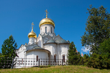 Fototapeta na wymiar White Church with Golden domes against a bright blue sky.