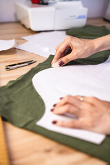 Selective focus of seamstress marking cloth near layout in workshop 