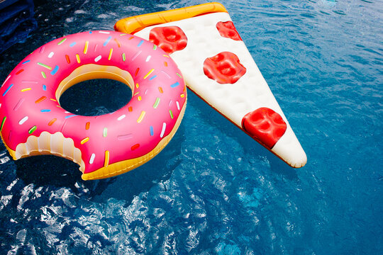 A pizza float and a pink donut float in a blue pool.