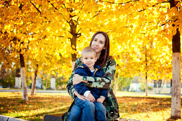 A young beautiful mother in warm clothes plays with her young son in the autumn Park.