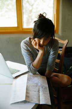 Woman planning a road trip with map and laptop
