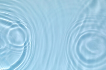 Blurred transparent blue colored clear calm water surface texture with splashes and bubbles. Trendy abstract nature background. Water waves in sunlight with copy space.