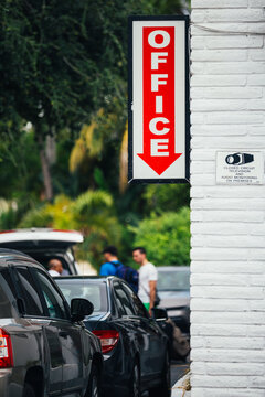 Office sign and video camera surveillance on a wall next to a parking lot