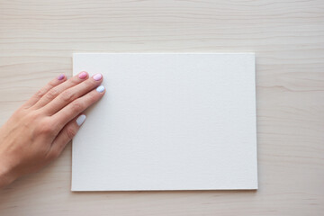 Obraz premium White board with hands for copy space. School office supplies on wooden background. Back to school concept. Top view ready for your design