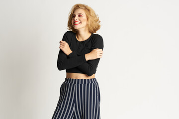 Pretty woman in black sweater striped pants fashion clothes light background studio
