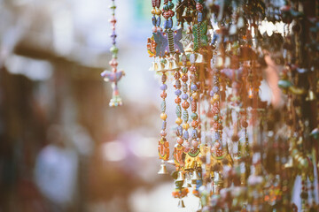 Decorative indian strings with animals, beads and bells with blurry street background.