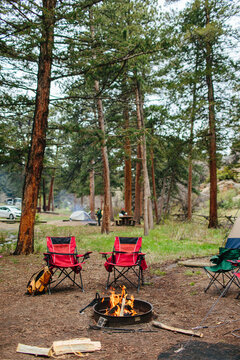 Folding camp chairs by an open pit fire in the forest