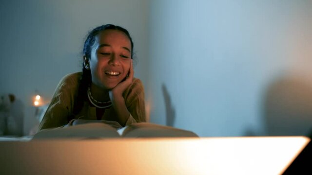 Ni&ntilde;a disfrutando de la lectura tumbada en la cama