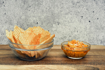 Fluted potato chips on a wooden board with sauce. Snack, ready meal menu, junk food. Close up.