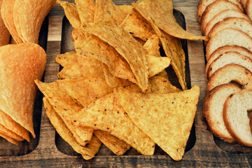 Mix of chips, snacks and crackers on a wooden stand. Unhealthy food, beer snack, ready meal. Close...