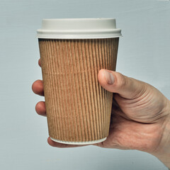 Paper cup in hand on a colored background. Eco-friendly materials in a coffee shop, biodegradable disposable tableware. Close up
