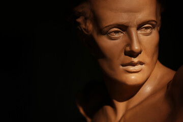Ritratto di giovane uomo, primo piano di testa in terracotta di provenienza europea, scultura su fondo scuro con spazio per testo 