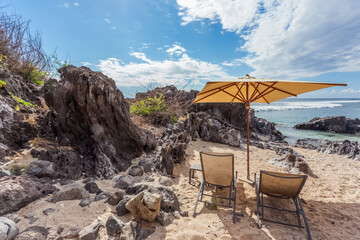 Transats et parasol de plage sur sable de crique déserte 