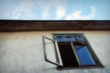 Open window and window pane against the wall of the house and the sky