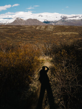 Protographer shadow taking a photo of snow covered mountains