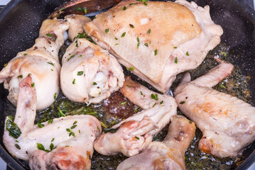 Cooking chicken with thyme and rosemary in a frying pan - close-up, top view