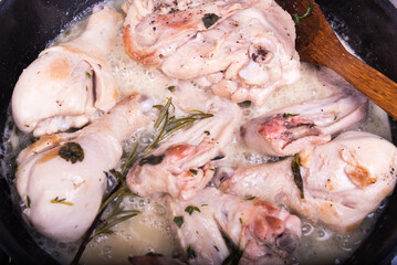 Cooking chicken with thyme and rosemary in a frying pan - close-up, top view