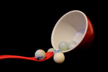 A red bowl with marbles and a spoon
