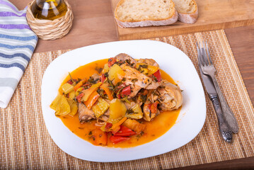 Italian chicken stew - chicken with bell peppers in a plate on a napkin with cutlery - classic Italian recipe, close-up, top view