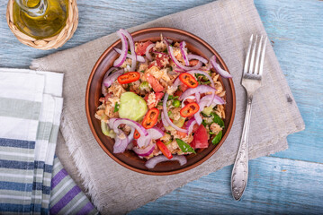 Italian tuscan vegetarian panzanella salad, mixed salad of breads, tomatoes and vegetables in a clay bowl on a linen napkin and a jug of olive oil on a wooden table