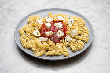 Pasta with tomato sauce and cheese on a marble table