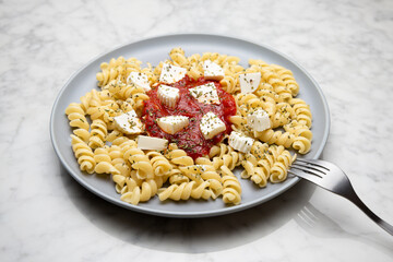 Pasta with tomato sauce and cheese on a marble table