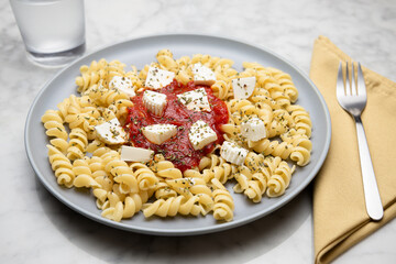 Pasta with tomato sauce and cheese on a marble table