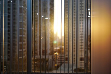 Sunset shining through the curtain and window  into room with blurred building and cityscape background.