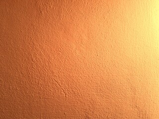Orange concrete wall background with texture and natural light.