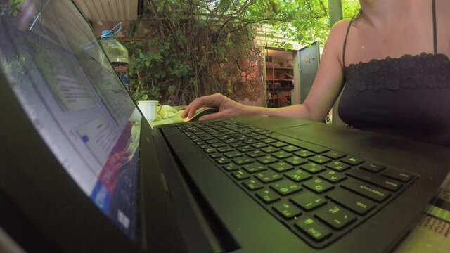Woman is sitting in garden and working a computer. Fish eye view