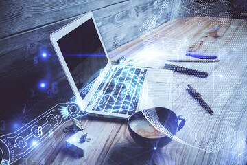 Computer on desktop in office with technology theme hologram. Double exposure. Tech concept.