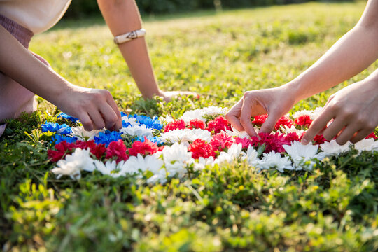 Hands of two girlfriends making an American flag out of flowers
