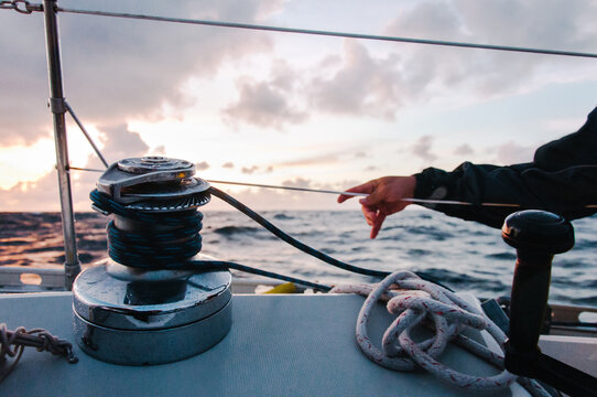 Hand on side of boat with sailing winch and boat line
