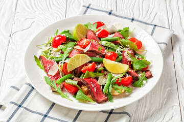 Close-up on a plate of sliced beef steak salad